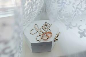 Wedding rings stand on a wooden box on a white background. The inscription love on a box for wedding rings. Wedding details. photo