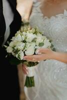 belleza Boda ramo de flores de blanco rosas en el manos de el novia foto