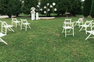 Boda ceremonia en el jardín. un lujoso Boda ceremonia. romántico Boda ceremonia. el soportes son decorado con vistoso flores blanco sillas foto