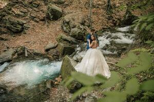 Boda Pareja es abrazando cerca el montaña río. novio y novia . naturaleza Boda Sesión de fotos. foto sesión en el bosque de el novia y novio.