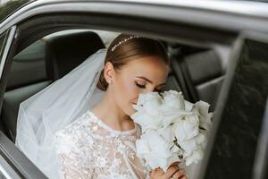 Bride smelling bouquet. Portrait of a beautiful bride with a wedding bouquet. Blonde girl with curly hair and fashion makeup. photo