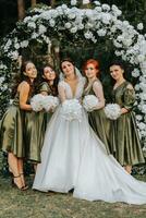 Bridesmaids smiling together with the bride. The bride and her fun friends celebrate the wedding after the ceremony in matching dresses. Bride and friends in nature photo