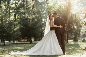 Romantic fairytale newlywed couple hug and kiss in forest at sunset photo