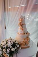 A white wedding cake, decorated with flowers and gold, stands on a glass stand. Fresh flowers at the wedding. sweets photo