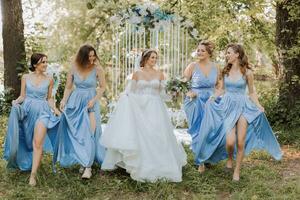 The bridesmaids in blue dresses, the bride is holding a beautiful bouquet. Beautiful luxury wedding blog concept. Spring wedding. photo