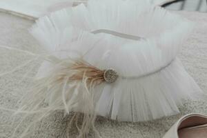 elegante nupcial liga decorado con plumas y joyas, en un gris antecedentes. preparación para vendaje el novia. foto