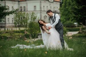 The groom bends the bride as if in a dance against the background of the castle. Groom in a vest. Portrait of the groom. Spring wedding photo