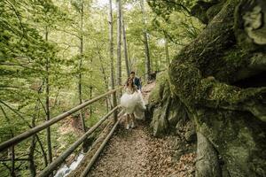 un contento Boda Pareja es corriendo a lo largo un bosque camino. novio y novia. Boda foto sesión en naturaleza. foto sesión en el bosque de el novia y novio.