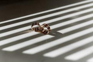 Two golden textured wedding rings on rays of falling light photo