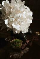 Morning of the groom and details, details of the groom on a dark background. men's watch, wedding rings in a glass box and wooden moss, a men's butterfly and a bouquet of white flowers photo