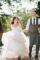 Groom and bride in the garden. Spring wedding in the park. Happy wedding couple running in the park. Stylish and beautiful. Princess dress. photo