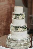 A three-tier wedding marble cake decorated with white roses and gypsophila stands on a glass stand. Decoration. Wedding. sweets photo