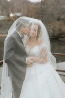 Groom and bride in the forest. Autumn wedding in the forest. Happy wedding, loving couple tender touches under the veil. Stylish and beautiful. Princess dress with a long train. photo