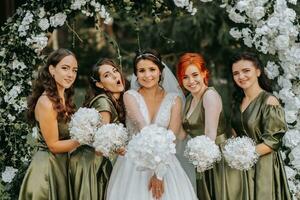 damas de honor sonriente juntos con el novia. el novia y su divertido amigos celebrar el Boda después el ceremonia en pareo vestidos. novia y amigos en naturaleza foto