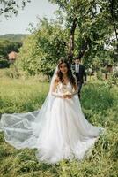 The first wedding meetings in the garden. A meeting of newlyweds on a green field in the open air, a surprise in nature. Front view of smiling bride waiting for groom. Wedding ceremony in the forest. photo