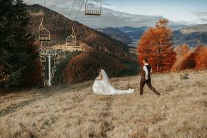 Wedding couple walking in the mountains. The groom goes straight to the bride. Against the background of a beautiful landscape photo