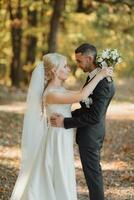 Groom and bride in the forest. Autumn wedding in the forest. Happy wedding, couple in love looking at each other. Stylish and beautiful. Princess dress with a long train. photo