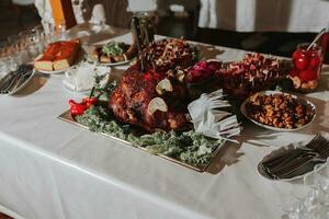 Buffet table at the wedding. An assortment of snacks on white plates standing on a Ukrainian-style tablecloth. Banquet service. Food, snacks with cheese, ham, prosciutto and greens. photo