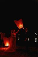 newly married couple embracing each other with the red Chinese sky lanterns in the background. photo