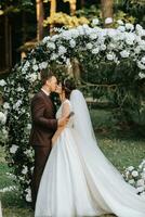 Beautiful wedding couple on the wedding autumn ceremony. the round arch is decorated with white flowers photo