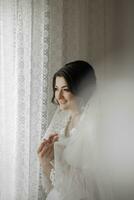 Portrait of a brunette bride touching her face. Gorgeous make-up and hair. Voluminous veil. Wedding photo. Beautiful bride photo