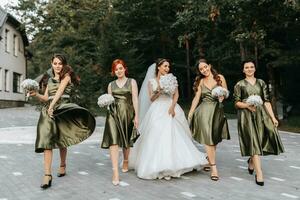 hermosa novia y su amigos- damas de honor teniendo divertido después Boda ceremonia. contento muchachas a su mejor amigos boda. hermosa y elegante novia con damas de honor caminando en el escalera foto