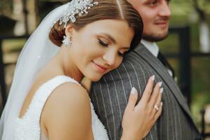 The bride and groom leaned their shoulders in the park. A couple of newlyweds, the bride and groom, at a wedding in the nature of green trees. photo portrait Wedding couple