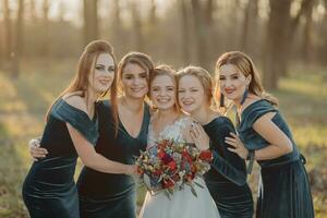 novia con damas de honor en el parque en el Boda día. damas de honor en azul vestidos y novia participación hermosa ramos de flores hermosa lujo Boda Blog concepto. verano boda. foto