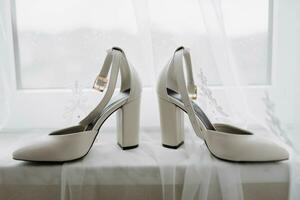 White elegant shoes. A pair of classic white shoes standing on a window sill on a white background. Fashion. Style. Wedding photo