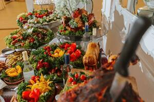 Buffet table at the wedding. An assortment of snacks on white plates standing on a Ukrainian-style tablecloth. Banquet service. Food, snacks with cheese, ham, prosciutto and greens. photo