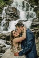 Portrait of a happy bride and groom near a waterfall. Bride and groom. Wedding photo session in nature. Photo session in the forest of the bride and groom.