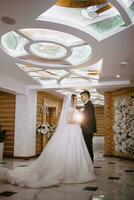 a beautiful bride in a wedding dress with a beautiful hairstyle and a groom in a black suit in a beautiful wooden interior photo