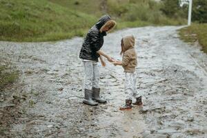 two happy little girls of European appearance playing in puddles during rain in summer. children are playing in the rain. child playing in nature outdoors. the girl enjoys the rain. photo