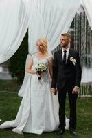 Wedding portrait. The bride and groom stand by the arch during the painting ceremony. Evening painting ceremony. photo