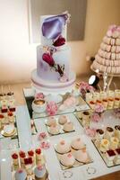 Delicious wedding reception candy bar dessert table full with cakes and sweets and flowers Chinese cherry blossoms on the background of an exquisite restaurant photo