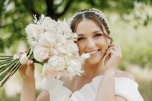 Beautiful bride with flowers in her hands, wedding nude makeup. Close-up portrait of a young gorgeous bride posing in her wedding morning suite. High quality photo