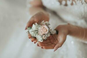 Boda detalles. el novia sostiene el del novio Boda flor en el ojal. manos doblada en el forma de un corazón. hermosa manos. francés manicura foto