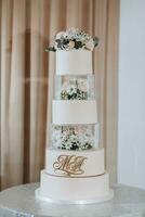 A white wedding cake, decorated with rose flowers, stands on a glass stand. Fresh flowers for a wedding. sweets photo