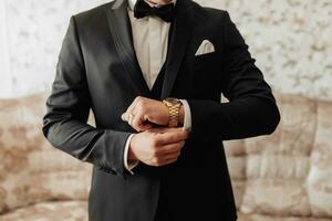 cropped photo of stylish man fixing black jacket. Front view. A stylish watch. Men's style. Fashion. Business