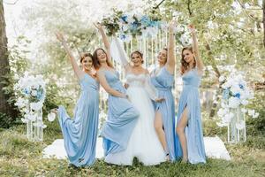 el damas de honor en azul vestidos aumento su manos, alegrarse, el novia es participación un hermosa ramo. hermosa lujo Boda Blog concepto. primavera boda. foto