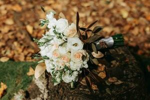 wedding bouquet on a tree. Wedding details on a wooden stump in the park. A beautiful bouquet of white flowers. photo