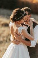 hermosa Boda Pareja riendo y besos en contra el antecedentes de piedras vestir con abierto espalda. alto calidad foto