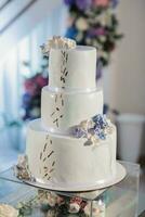 un blanco Boda pastel, decorado con flores y oro, soportes en un vaso pararse. Fresco flores a el boda. dulces foto