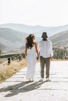 Stylish groom in white shirt and cute brunette bride in white dress in forest near wedding wooden arch. Wedding portrait of newlyweds. photo