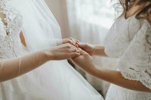 Morning of the bride. The bridesmaid helps the bride, supports her and holds her hands. Girlfriends help the bride. photo