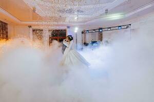 the first dance at the wedding of the bride and groom in an elegant restaurant with great lighting and atmosphere. Heavy smoke photo