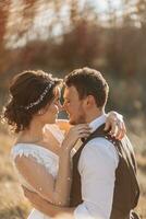 Beautiful wedding couple laughing and kissing against the background of stones. Dress with open shoulders. High quality photo