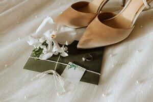 wedding accessories in light colors, shoes, a wedding ring and a wedding bouquet. Invitation from embossed paper in green color photo