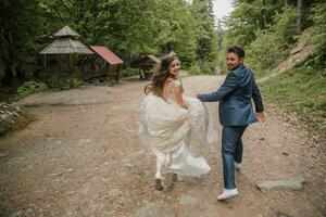 A happy wedding couple is running along a forest path. Groom and bride. Wedding photo session in nature. Photo session in the forest of the bride and groom.