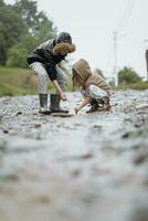 two happy little girls of European appearance playing in puddles during rain in summer. children are playing in the rain. child playing in nature outdoors. the girl enjoys the rain. photo
